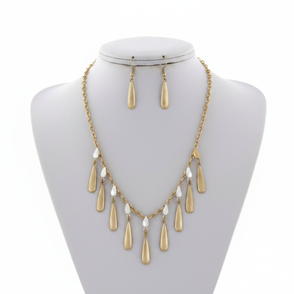 Gold necklace and earrings on a mannequin bust with a white background