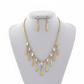 Gold necklace and earrings on a mannequin bust with a white background