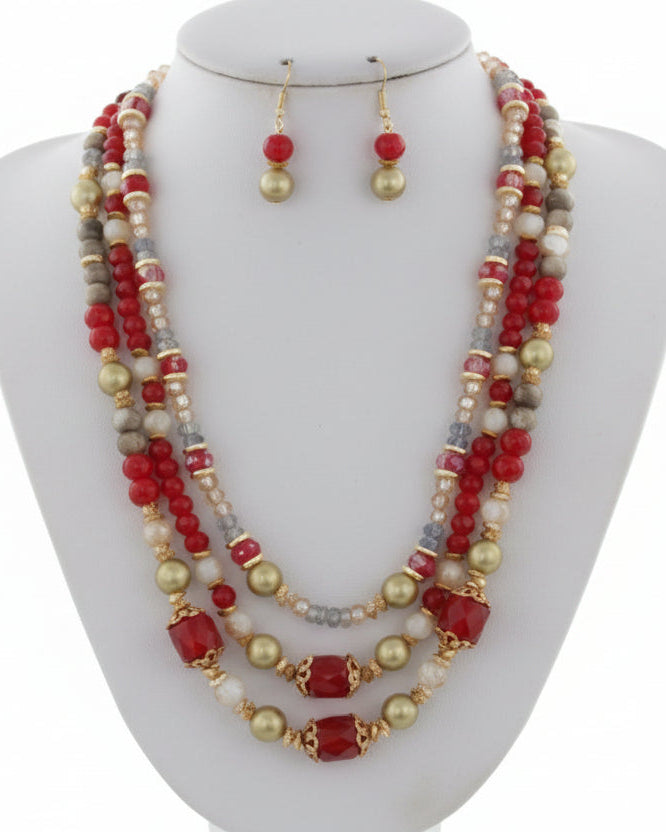 Necklace and earrings set with red and gold beads on a white background