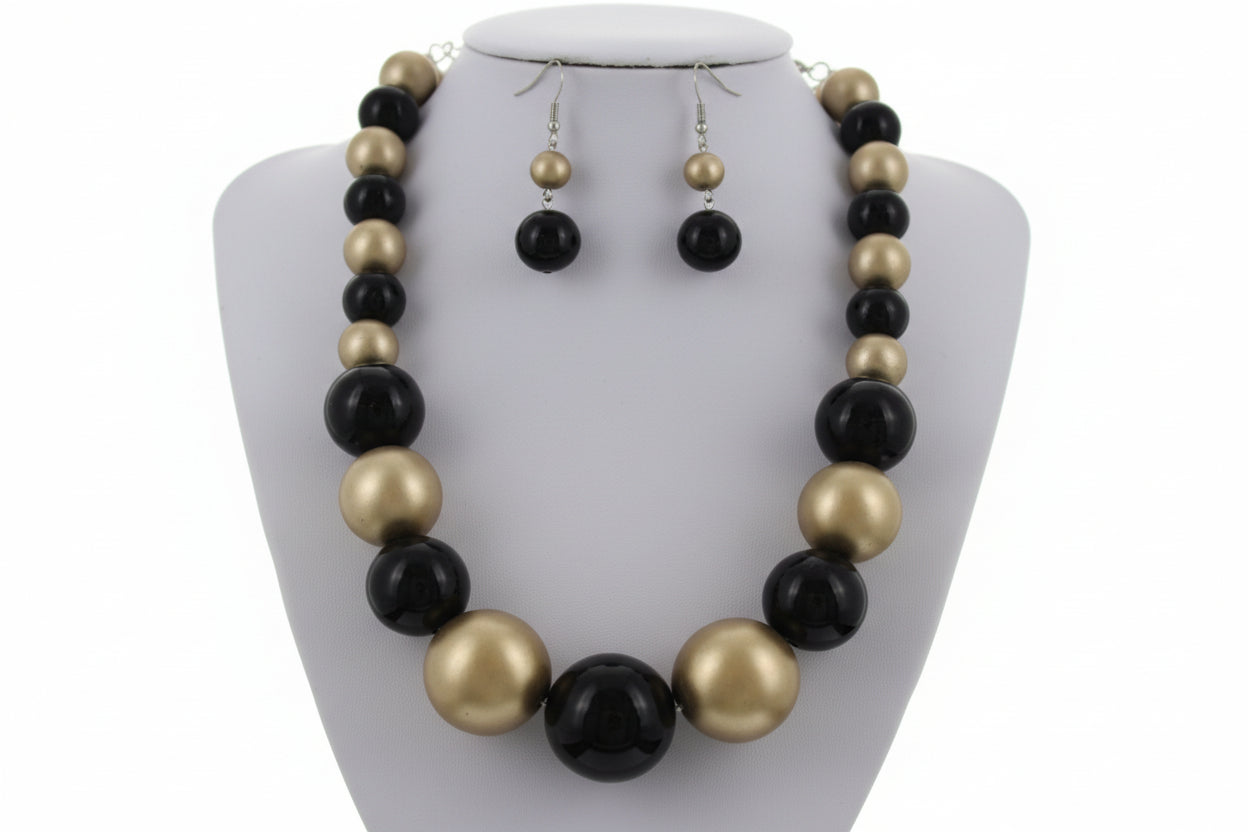 Black and gold necklace set with matching earrings on a white background