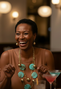 Woman smiling at a social gathering with drinks and people around