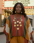 Woman in a colorful outfit standing in front of a theater marquee.