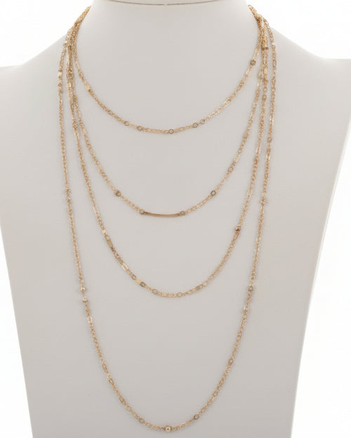 Set of gold necklaces on a mannequin bust against a white background