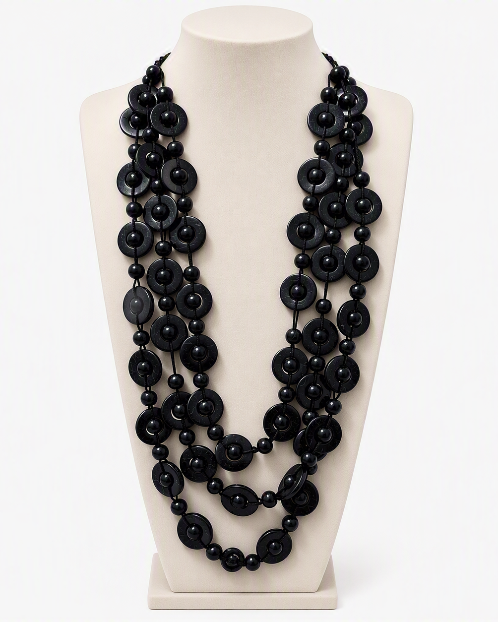 A multi-strand black beaded necklace displayed on a cream-colored mannequin bust against a white background.