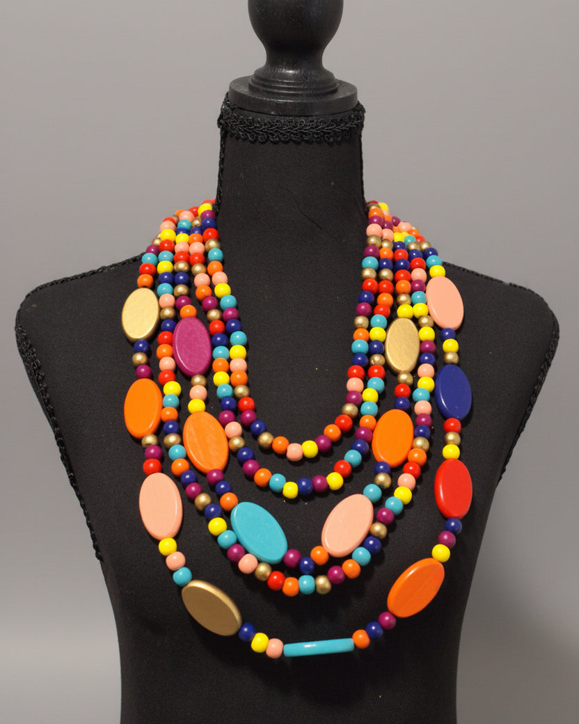 A multi-strand statement necklace with colorful round and oval beads displayed on a black mannequin bust against a black background.