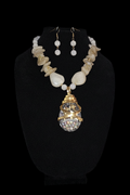 Necklace with a large crystal pendant and matching earrings on a black stand.